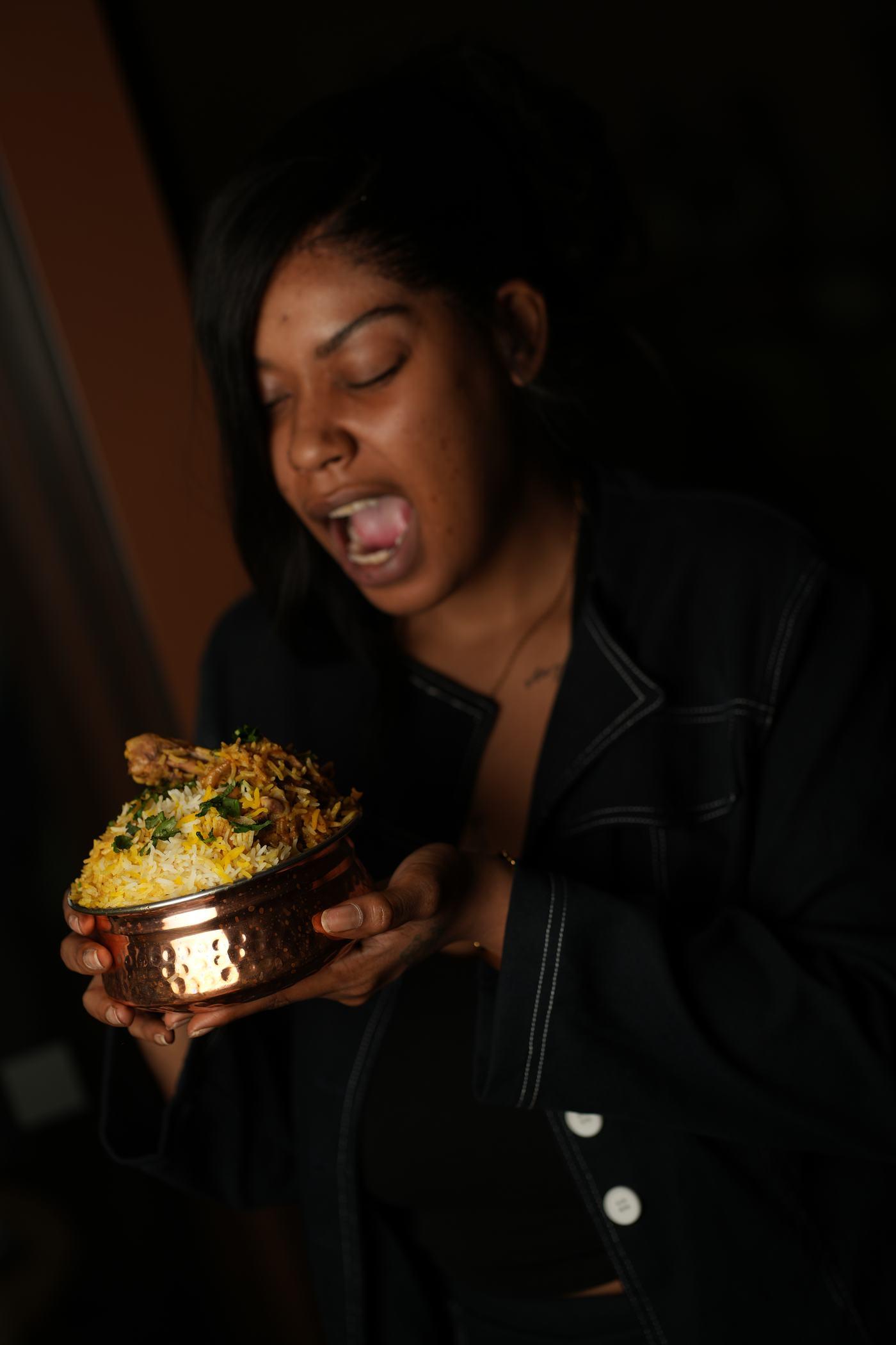 A guest laughing as she lifts a bowl of food at Aara