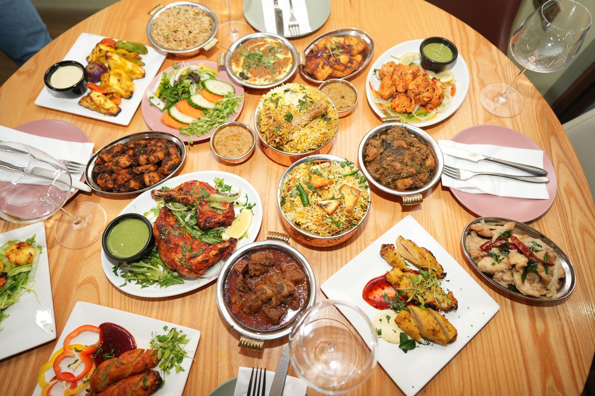 A full table of shared dishes laid out for guests at Aara